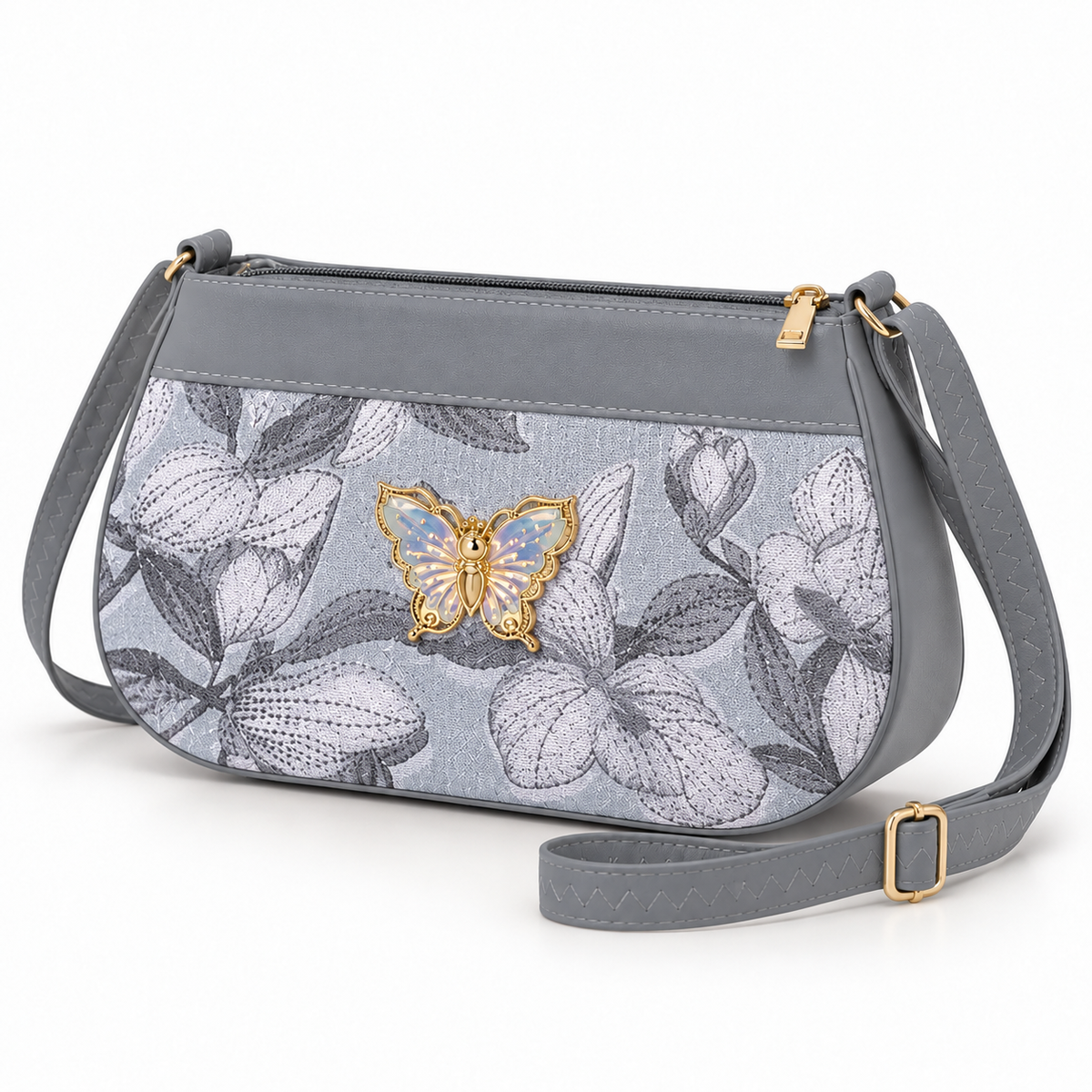 Grey floral shoulder bag shown at an angle, with white flowers and dark leaves, a pale iridescent butterfly, top zipper and grey strap with gold-tone buckle.