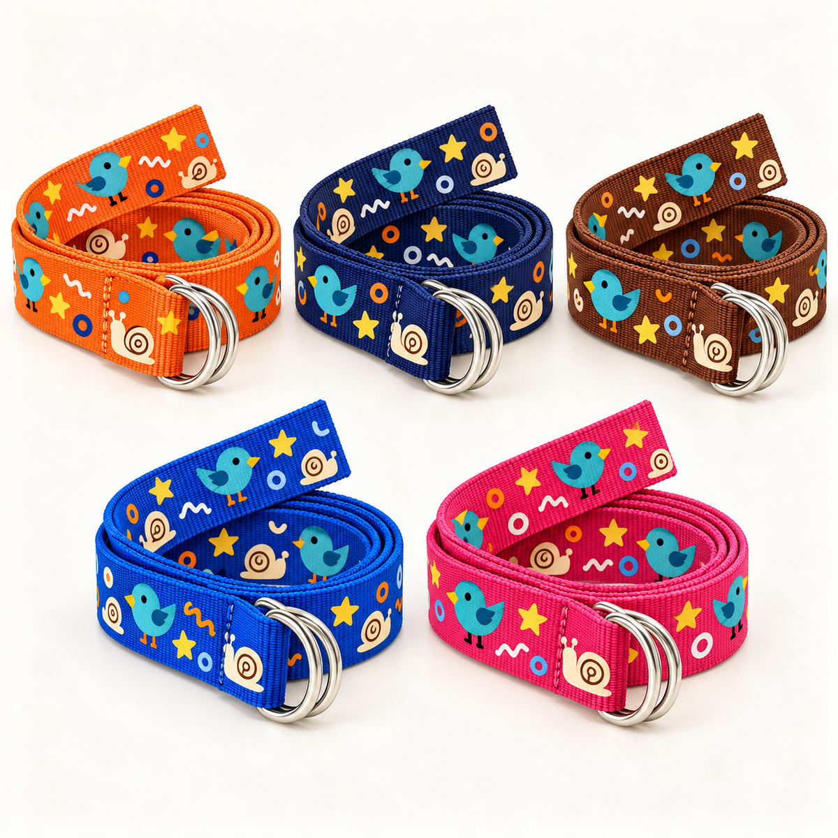Five nylon webbing belts in orange, navy, brown, blue and pink arranged as neat coils, each with a double silver-tone D-ring buckle and an original bird, snail, star and circle print on a warm-white background.