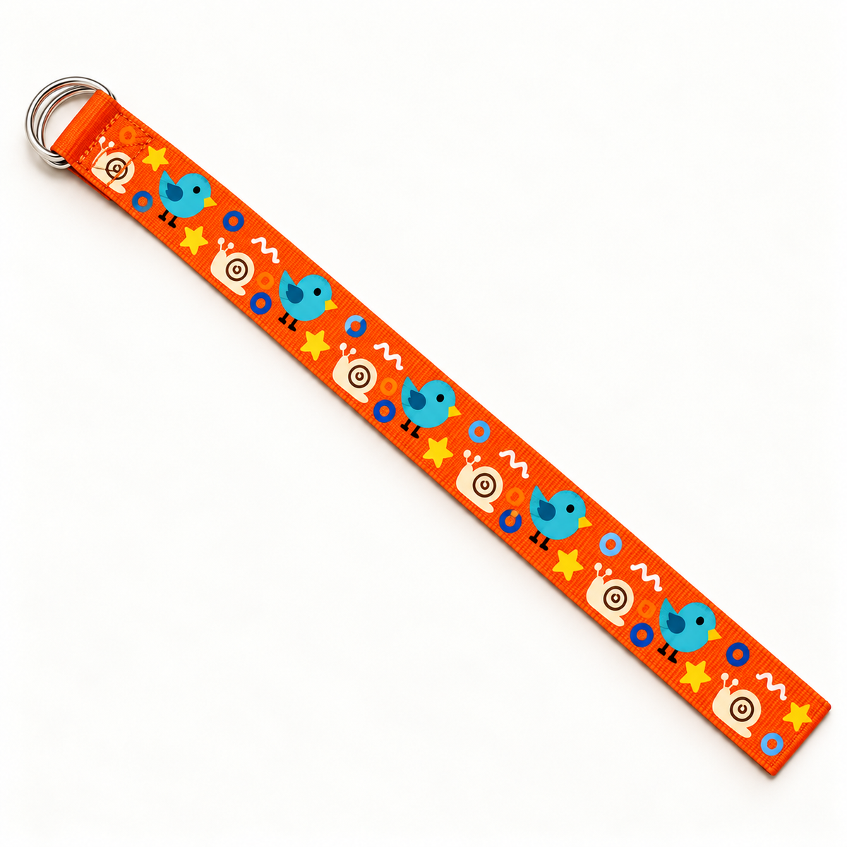 Orange nylon webbing belt laid diagonally at full length, showing its double D-ring buckle, straight-cut end and original bird, snail and abstract-shape print on a warm-white background.