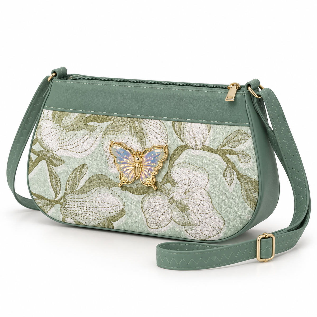 Sage green shoulder bag in three-quarter view with a cream floral pattern, pale iridescent butterfly ornament, top zipper and buckled green strap.