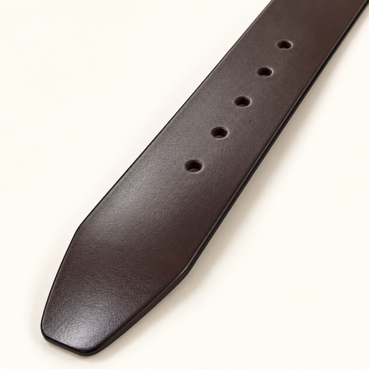 Close-up of round adjustment holes and the tapered tip of the smooth dark brown belt.
